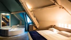A modern bedroom with a curved vanity, a large mirror, a bed with white linens, and a wooden ceiling. - Les Ursulines (Autun)