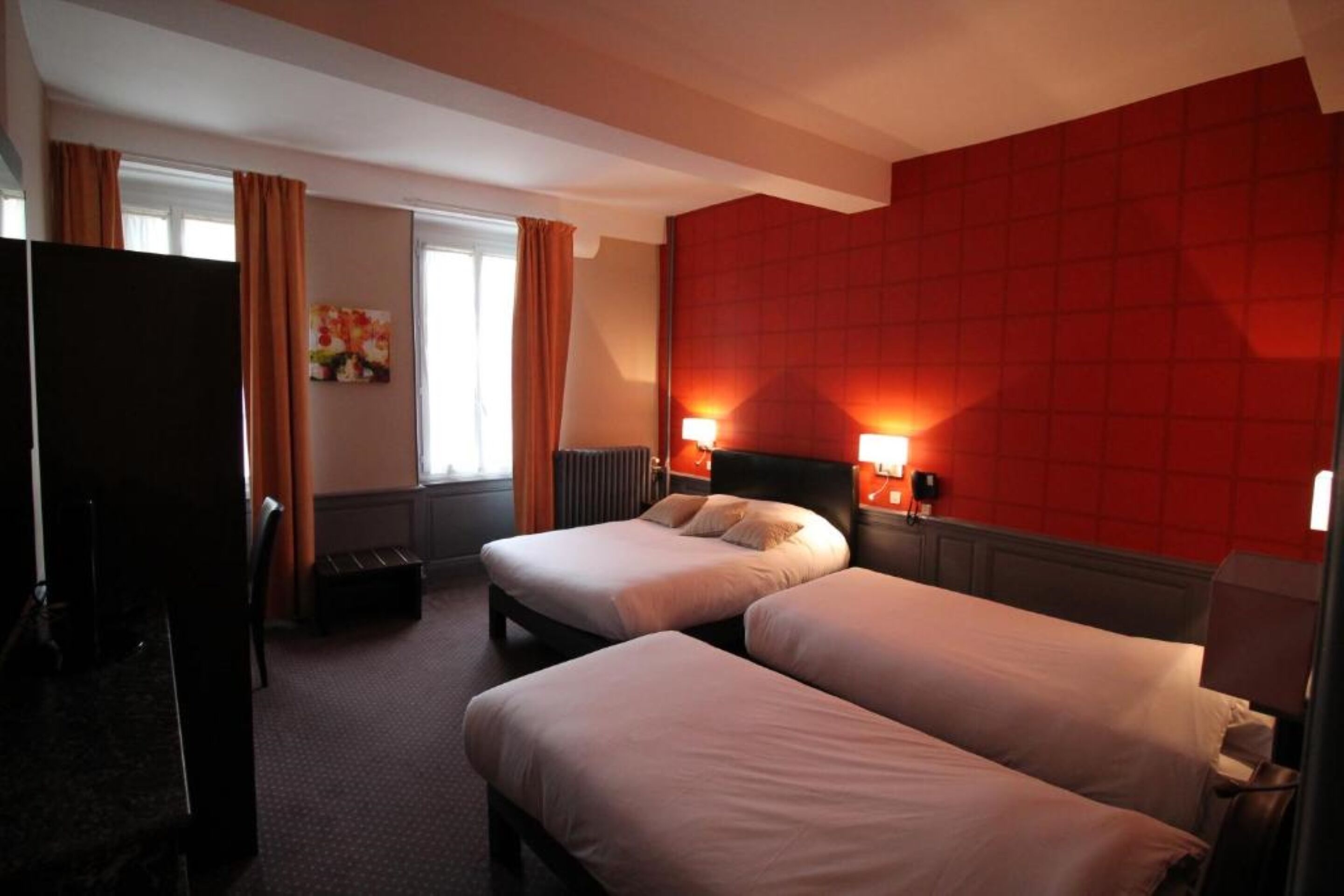 Et hotelværelse med to senge, et fjernsyn og en rød væg.