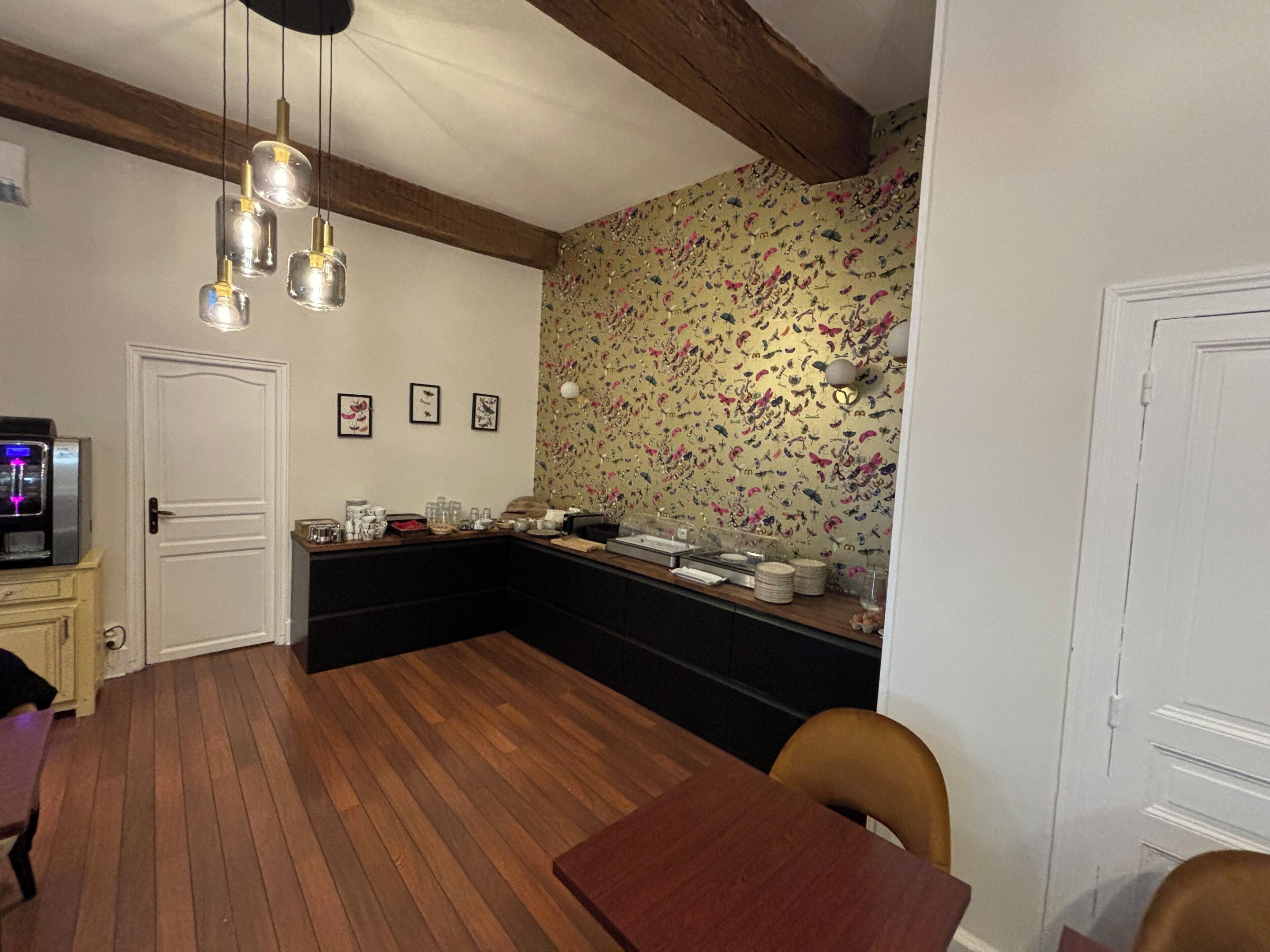 Una cocina con piso de madera, una mesa de comedor y una encimera con diversos utensilios de cocina.