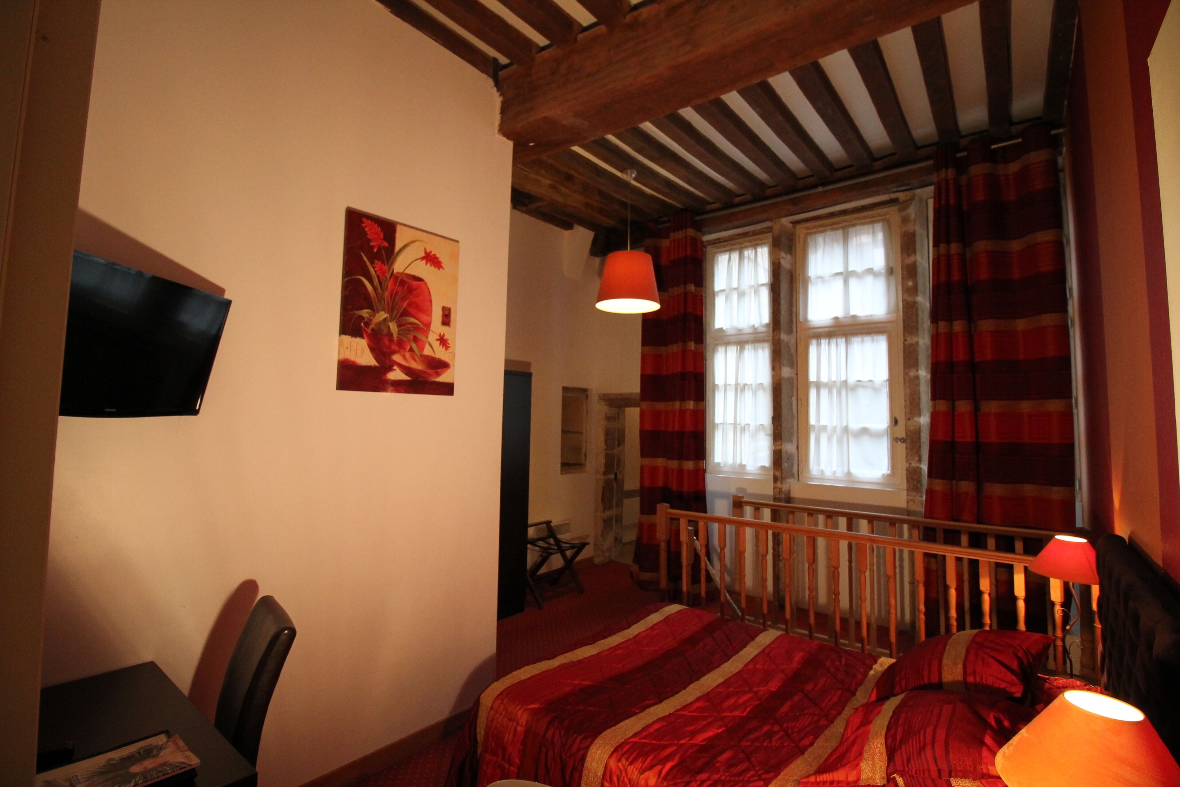 Un dormitorio con cama, escritorio, silla, televisor y ventana con cortinas.