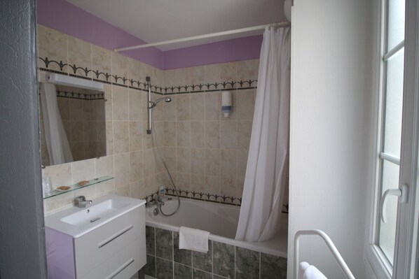 Un baño con un lavamanos blanco, un estante de vidrio, una bañera y una ducha.