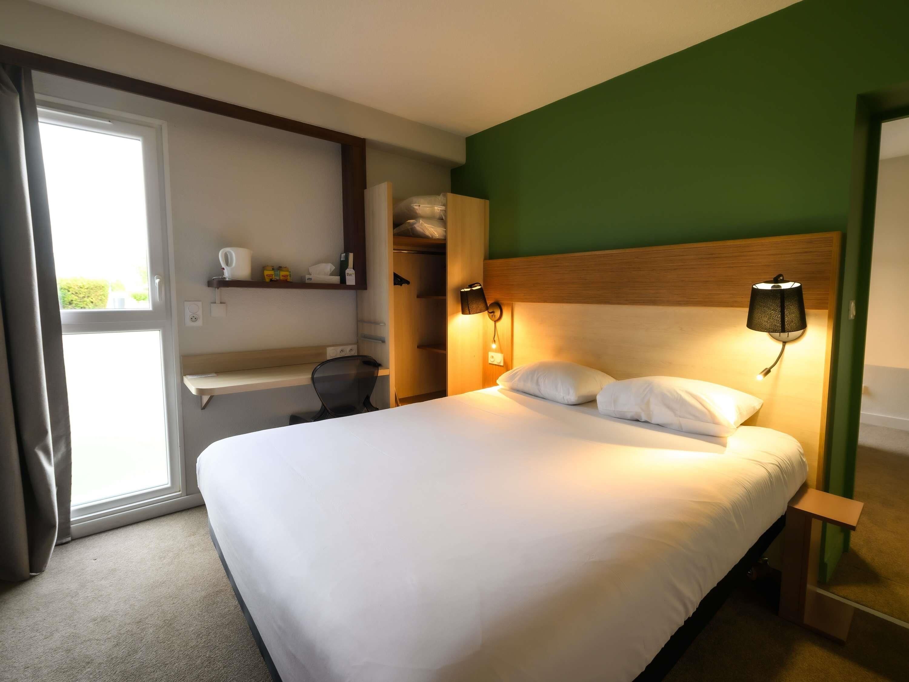 Ein Hotelzimmer mit Bett, Nachttischen, einem Kleiderschrank und einem Fenster.
