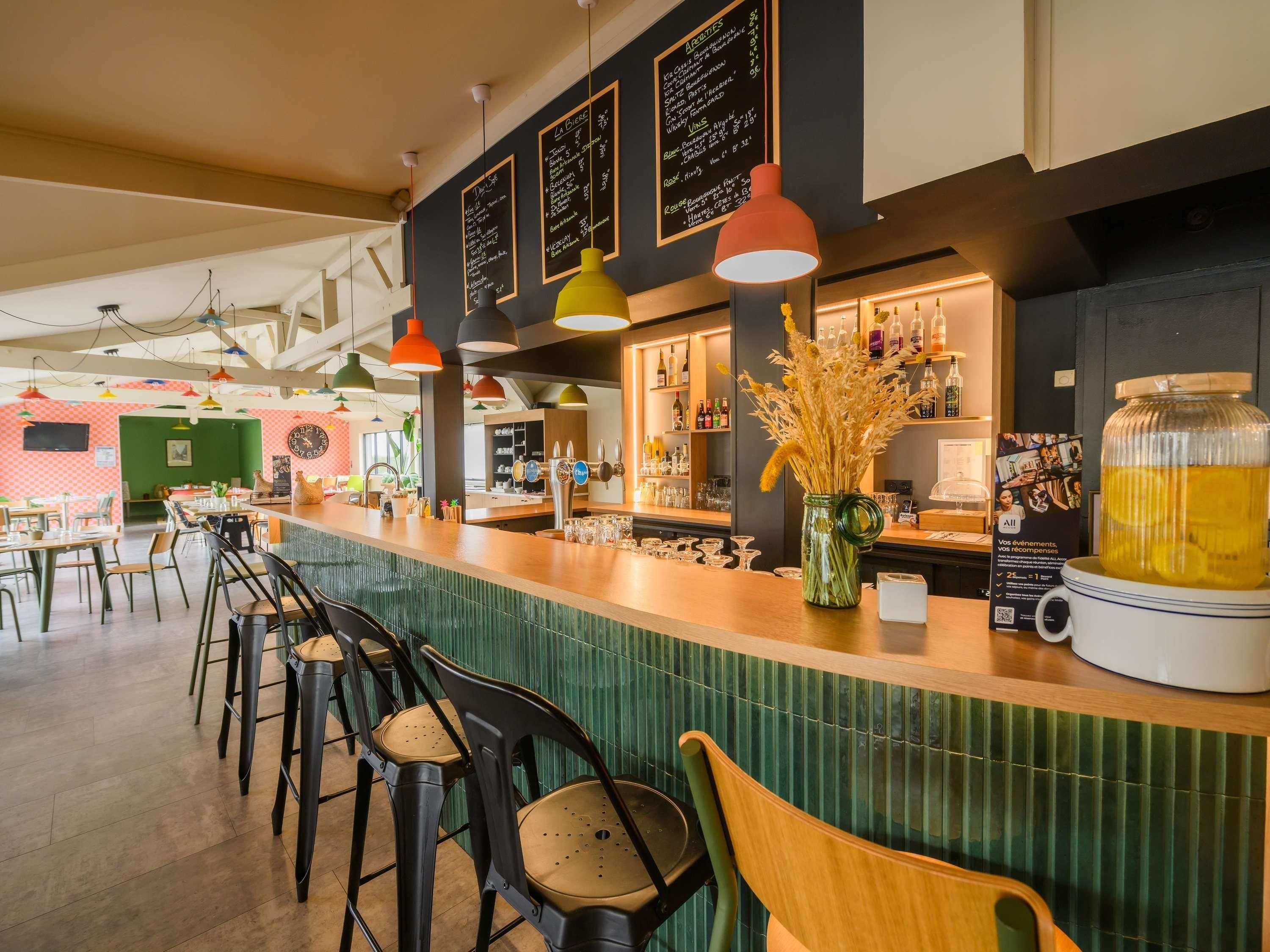 Eine Bar mit einer Theke, Hockstühlen und einer Auswahl an Flaschen und Gläsern.