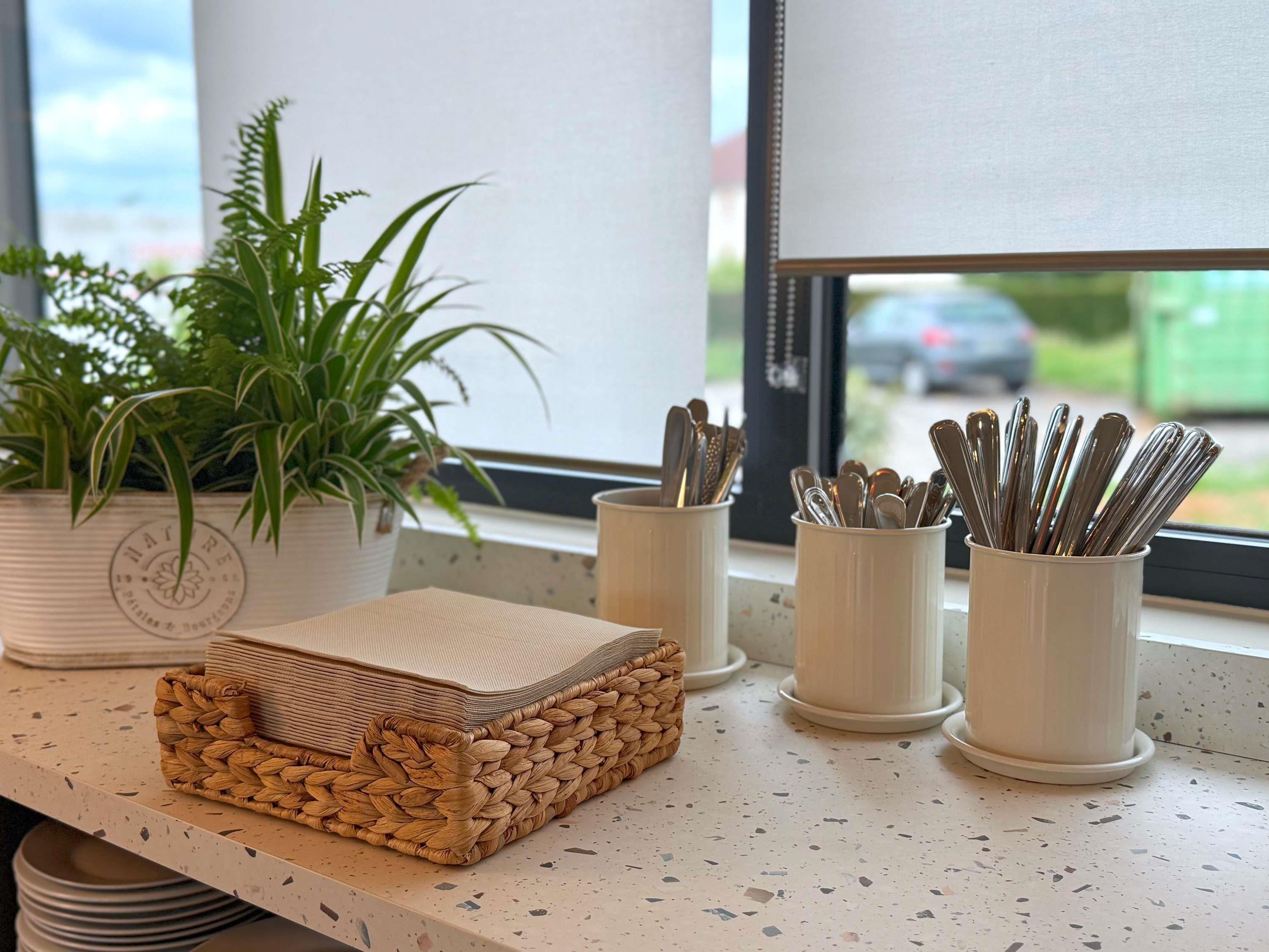 A kitchen counter with a woven basket, potted plants, and utensil holders.