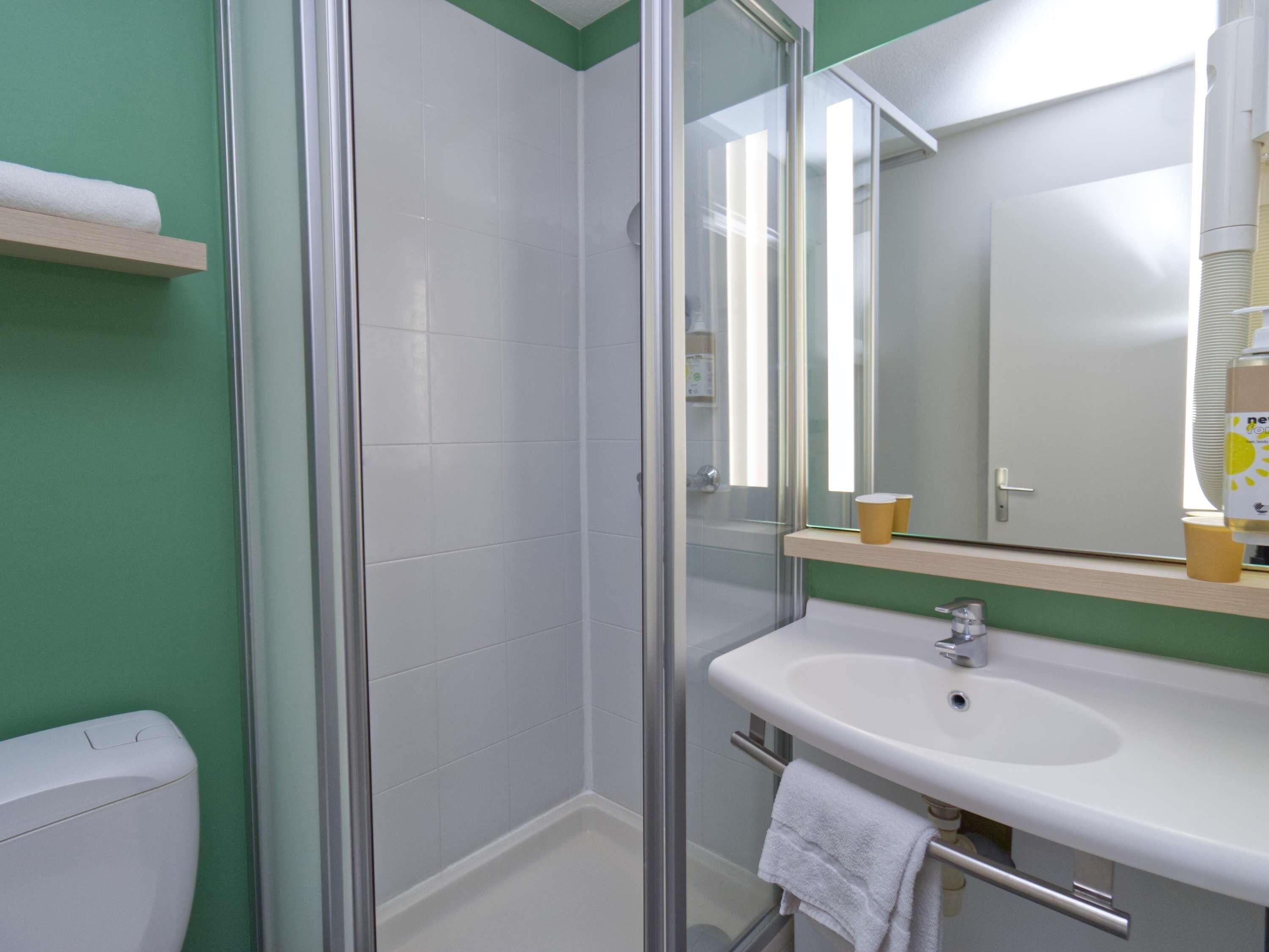 A bathroom with a glass shower enclosure, a white sink, and a mirror above it.