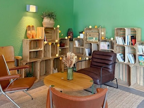 A room with a green wall, wooden furniture, a round wooden table, and a brown leather chair. - greet Hotel Dijon Sud Longvic (Longvic)