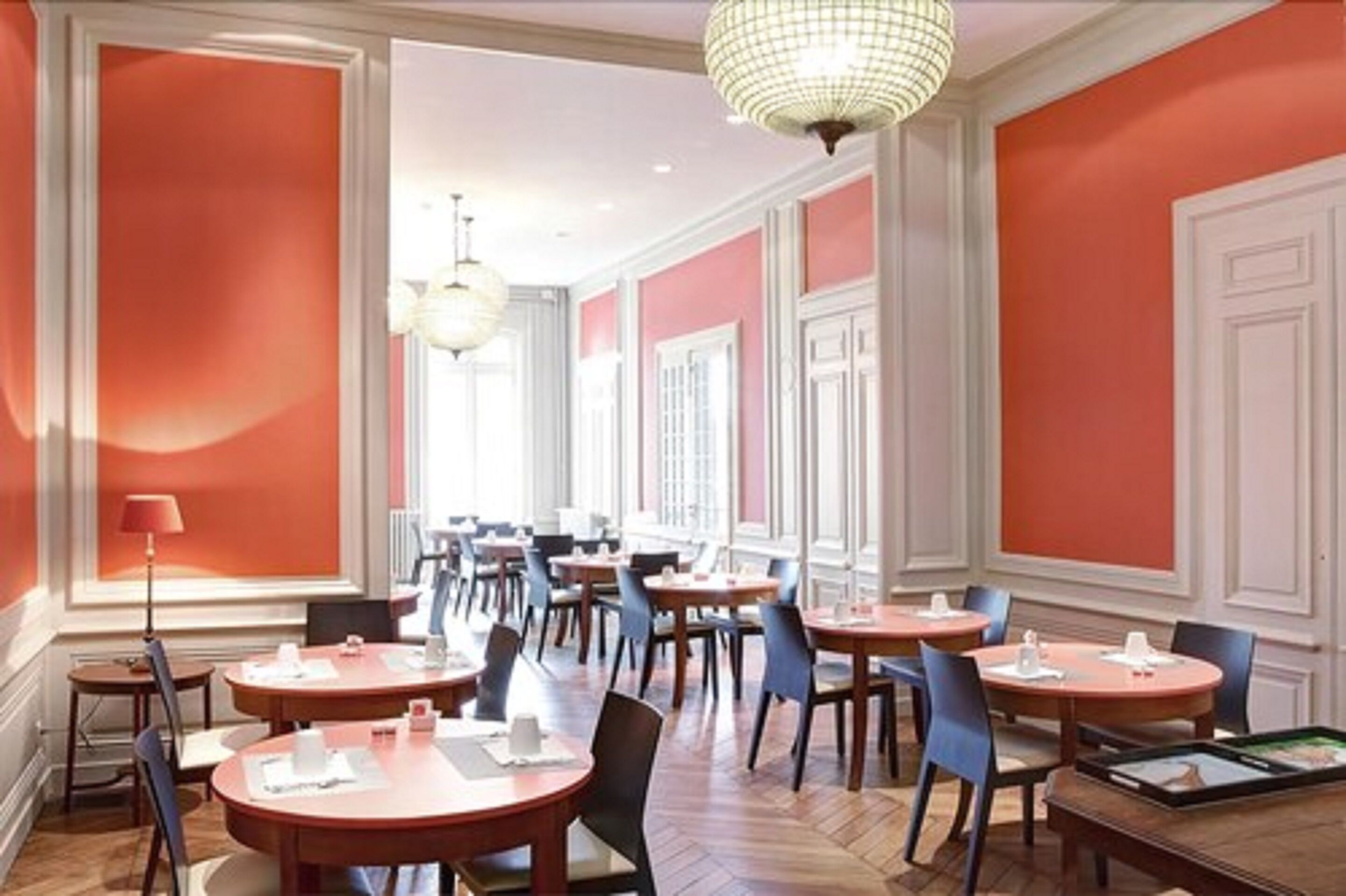 Ein Hotel-Speisesaal mit runden Tischen, Stühlen und einer Kronleuchter.