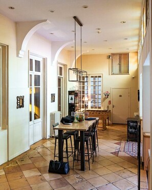 Un comedor amplio con techo alto, una mesa central con sillas y un colgador de luz.