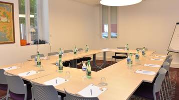 A conference room with a long table, chairs, water bottles, and a whiteboard.
