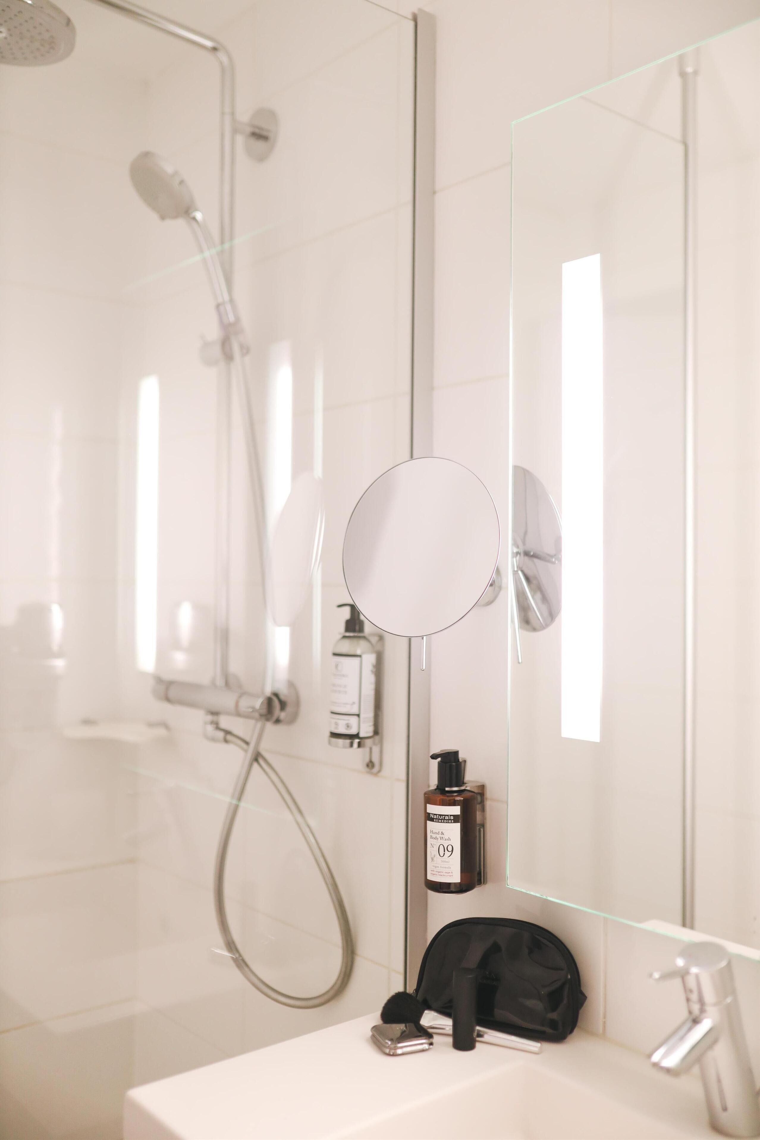 Ein modernes Badezimmer mit Duschkabine aus Glas und mehreren Handbrausen.