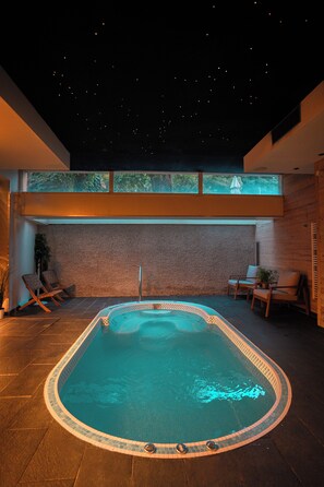 A swimming pool with a tiled edge, surrounded by lounge chairs and a stone wall. - Château & Spa de la Commanderie (Eybens)