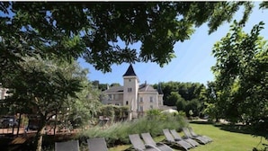A large building with a tower, surrounded by a well-maintained lawn and several lounge chairs. - Château & Spa de la Commanderie (Eybens)