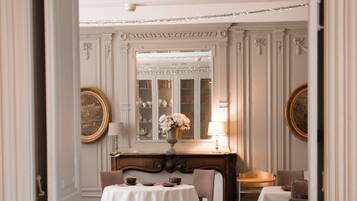 A dining area with tables set for four, a wooden desk, and a mirror above the desk.