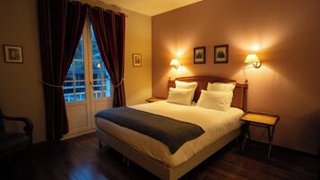 A hotel room with a large bed, two bedside lamps, a wooden nightstand, a chair, and a window with curtains.