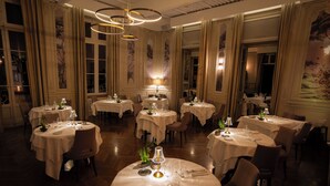 A restaurant with round tables, chandeliers, and classic decor. - Château & Spa de la Commanderie (Eybens)