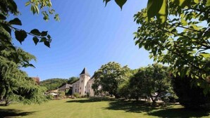 A large, historic building with a prominent tower, surrounded by well-maintained lawns and trees. - Château & Spa de la Commanderie (Eybens)