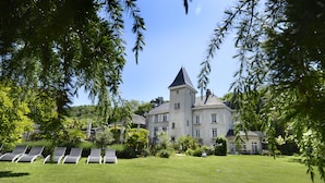 A large, historic building with a tower, surrounded by a well-maintained lawn and several lounge chairs. - Château & Spa de la Commanderie (Eybens)