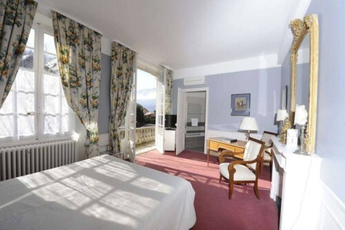 A hotel room with a bed, a desk, a chair, a mirror, and a view of the outside.