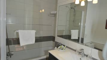 A modern bathroom with a glass-enclosed shower, a vanity with a mirror, and a towel rack.