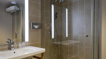 Une salle de bain moderne avec une douche à parois de verre, un lavabo blanc et un grand miroir.