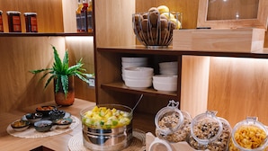 Una mesa de desayuno tipo buffet con diversos alimentos y recipientes.