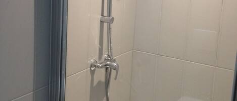 A glass-enclosed shower with a chrome showerhead and a handheld shower attachment.
