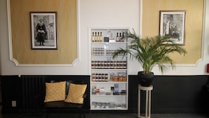 A reception area with a black sofa, patterned cushions, a white display case with various items, and two framed pictures on the walls. - Regina Hotel (Avignon)