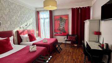 Habitación de hotel con dos camas, un escritorio, una silla, un televisor y un cartel en la pared.