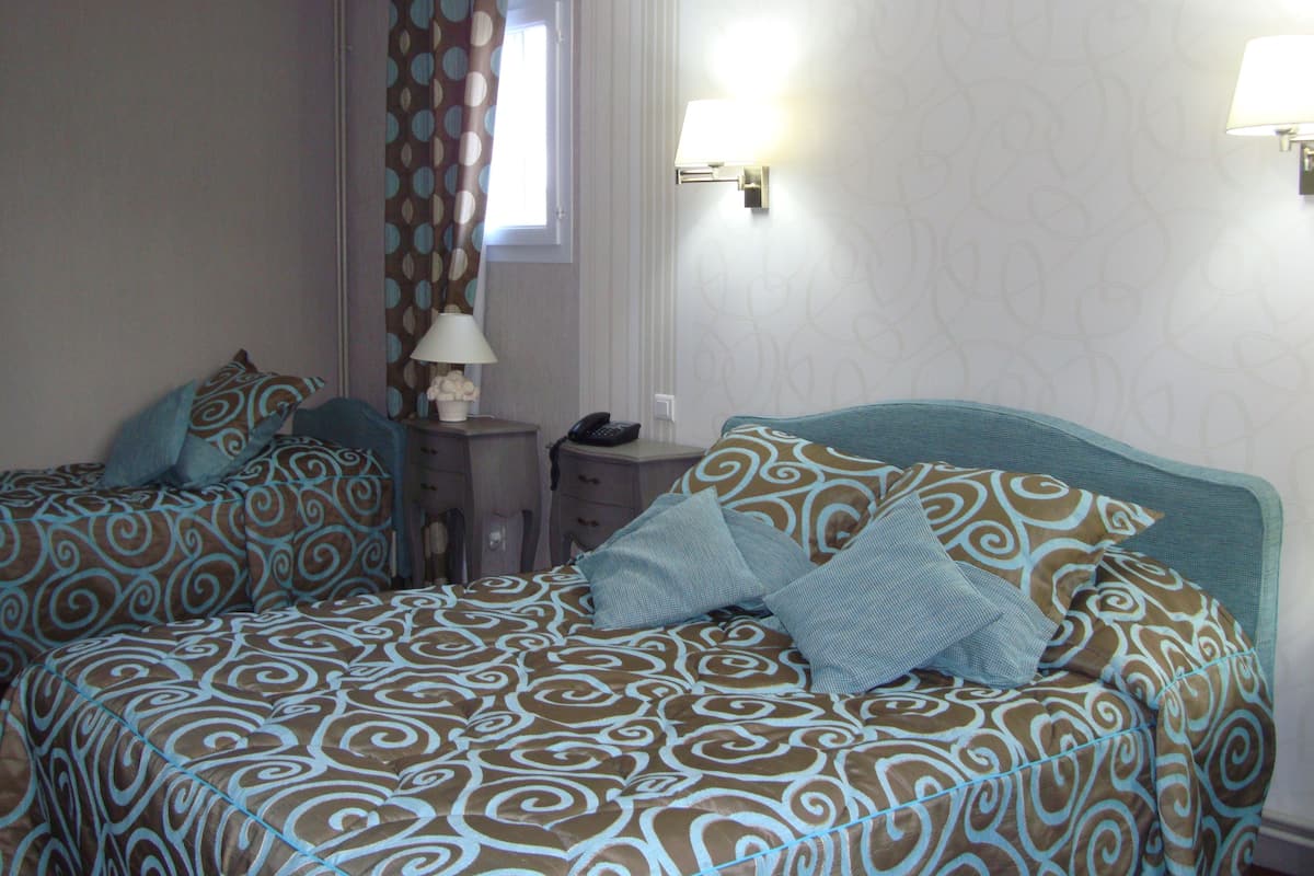 Une chambre d’hôtel avec deux lits, une table de chevet, une lampe et un téléphone.