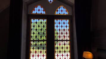 A set of stained glass doors with geometric patterns and a lamp to the right.