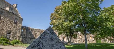 A stone pyramid in a courtyard with a historic building in the background.