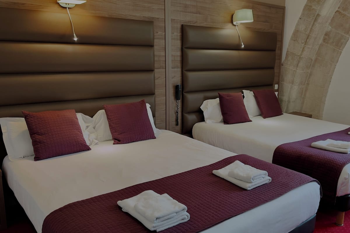 Two double beds with headboards, a phone on the wall, and a red carpet.
