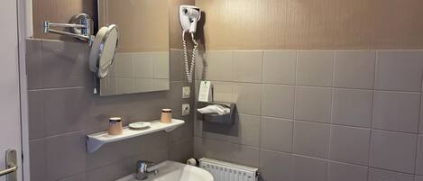 Baño con lavamanos, espejo, dispensador de toallas y secador de pelo.