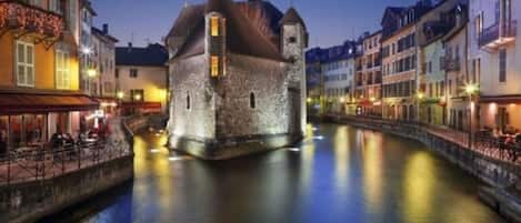 Edifici de pedra històric amb una torre, ubicat al costat d'un canal flanquejat per edificis.