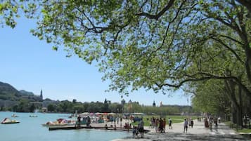 Un parco sul lago con barche, persone e alberi.