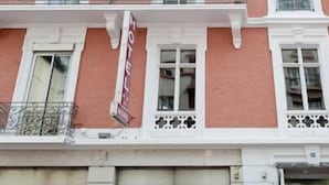 Fachada de hotel con una combinación de colores rojo y blanco, varias ventanas y un letrero que indica que es un hotel.