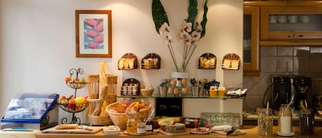 A breakfast buffet with various food items, a coffee machine, and decorative vases on the counter.