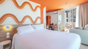 A hotel room with a bed, a desk, a chair, and a sofa.