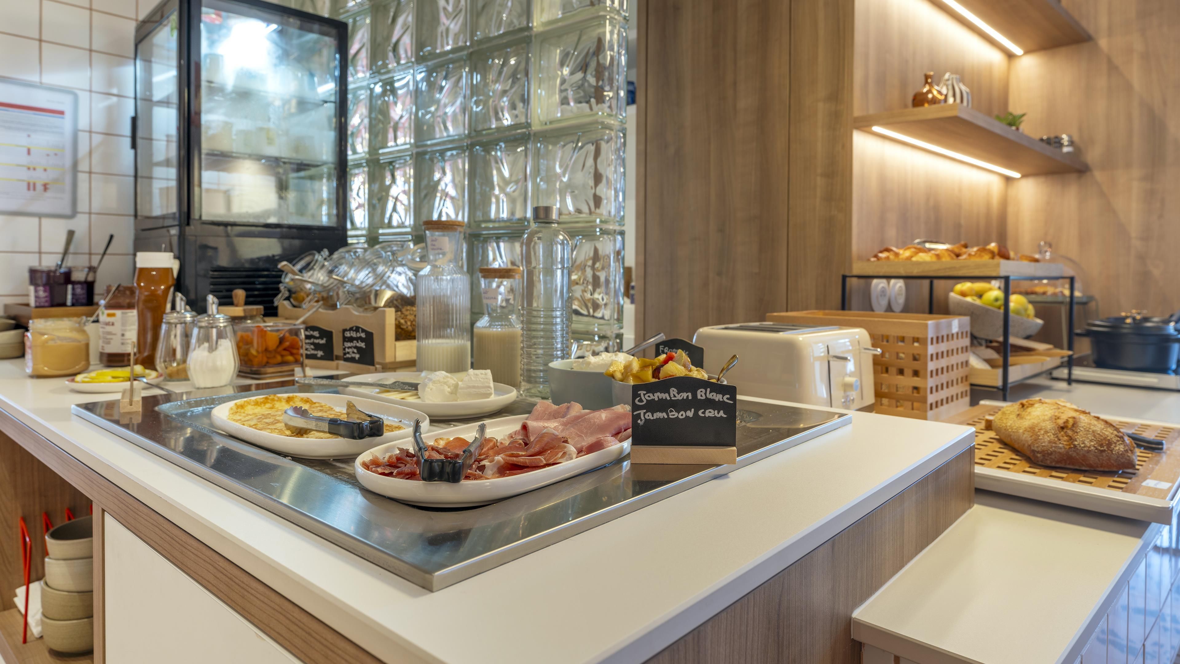 Ein Frühstücksbuffet mit verschiedenen Speisen und einem Schild mit der Aufschrift 'Jampon Barbic'.
