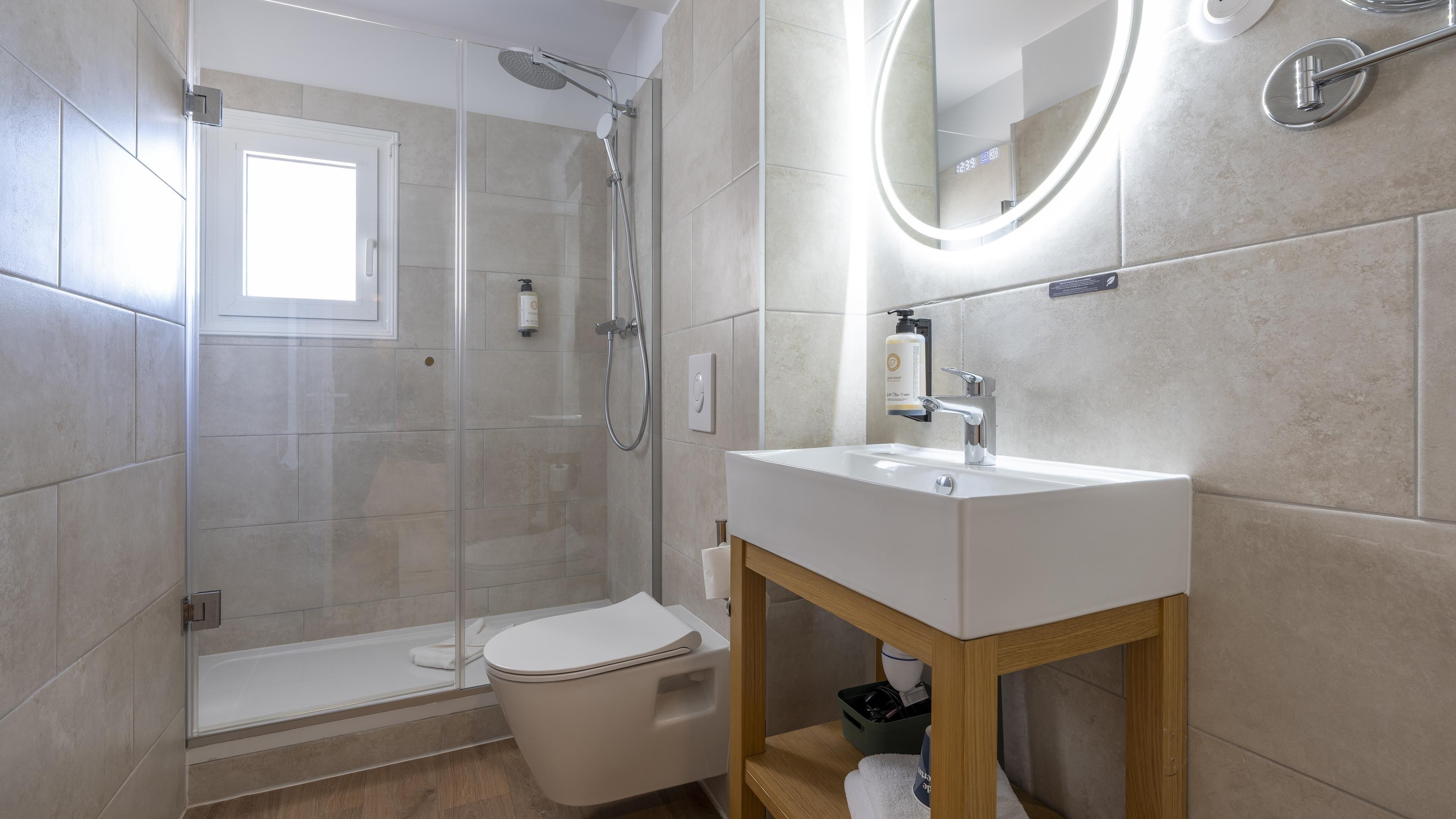 A modern bathroom with a glass-enclosed shower, a white toilet, and a sink with a wooden vanity.