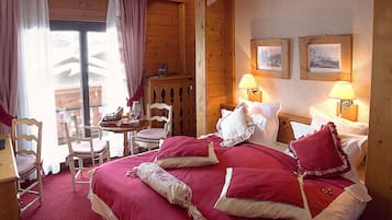 A wooden cabin-style room with a large bed, two bedside tables with lamps, a wooden chair, and a small table with a basket.