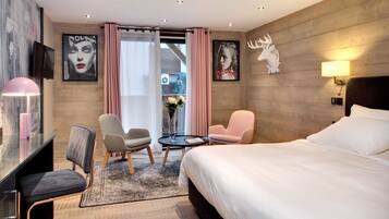 Una habitación de hotel moderna con una cama grande, dos sillones, un escritorio y un televisor.