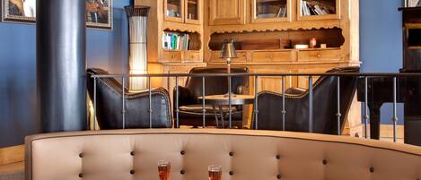 A dining area with a round table, two chairs, and a bar stool. There are two glasses of a pink beverage on the table.