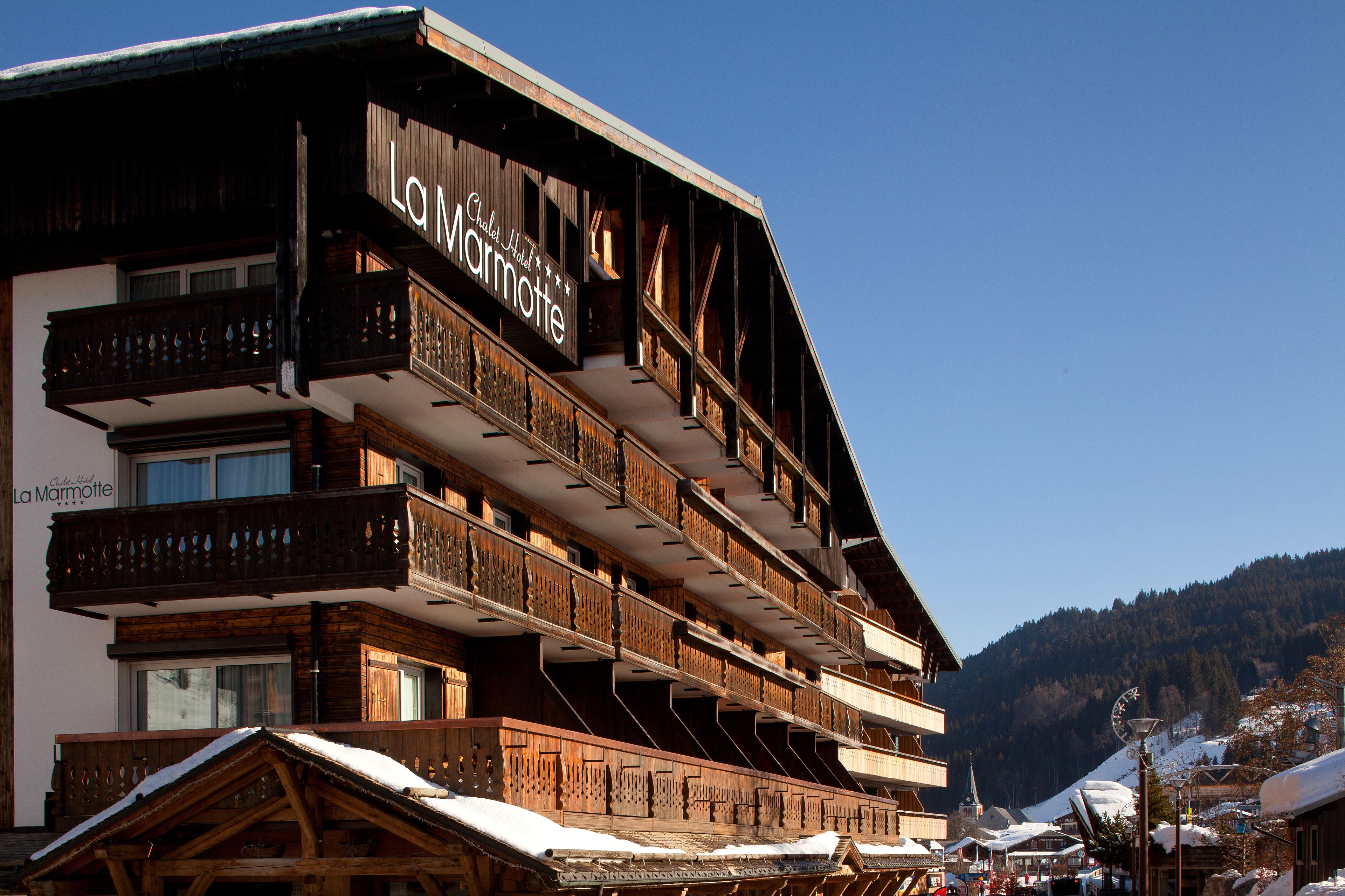 A multi-story wooden building with balconies and a sign reading "La Marmotte."