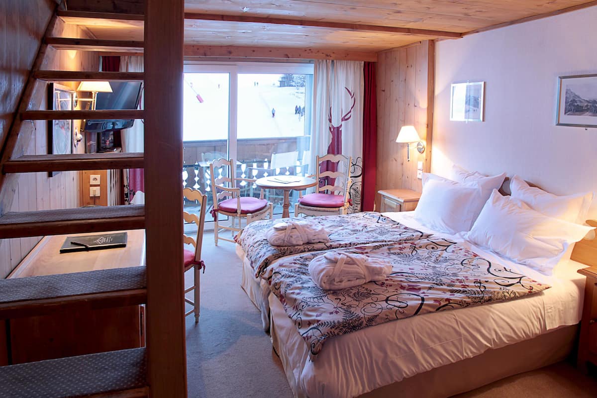 Habitación de hotel con cama, escritorio, silla y ventana con vista a un paisaje nevado.