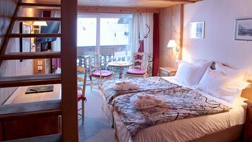 Habitación de hotel con cama, escritorio, silla y ventana con vista a un paisaje nevado.