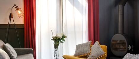 A modern living room with a sofa, armchair, and a small table with a vase of flowers.