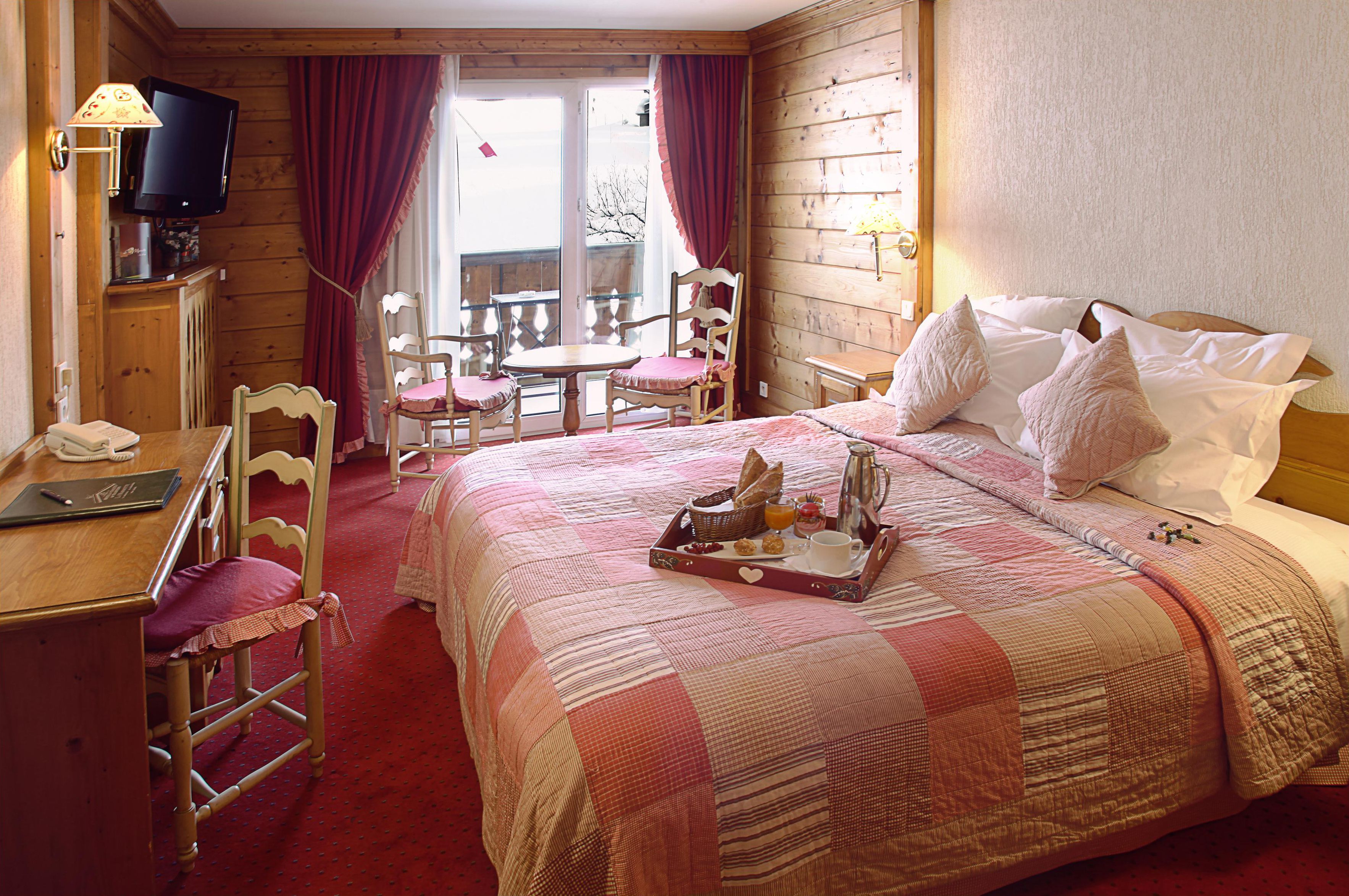 Una habitación acogedora con una cama, un escritorio con teléfono, televisión y una bandeja de desayuno sobre la cama.