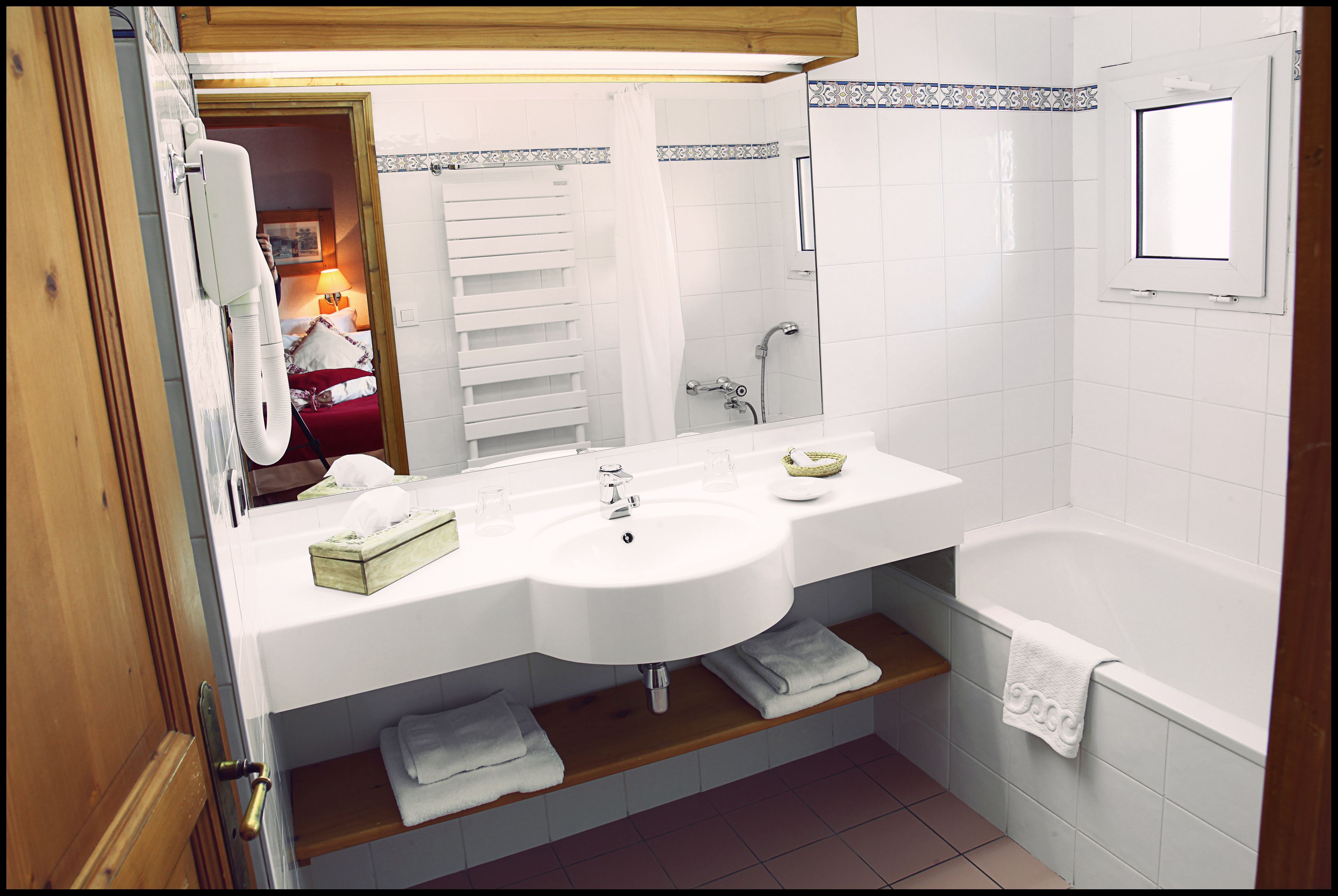 A bathroom with a sink, mirror, and bathtub.