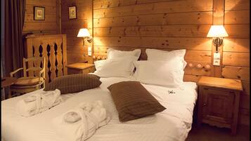 A wooden-paneled room with a bed, two nightstands, a chair, and a lamp.